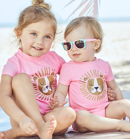 Two blonde girls in matching pink beach outfits from carter's