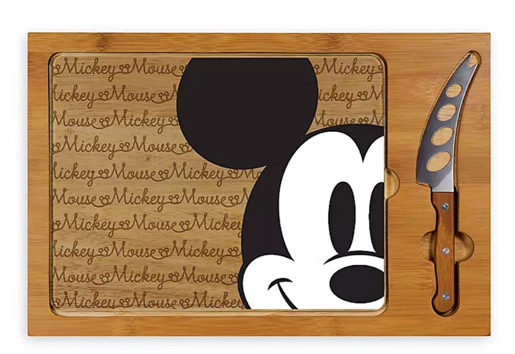 A cheeseboard has Mickey Mouse on the front and a cheese knife on the side. 