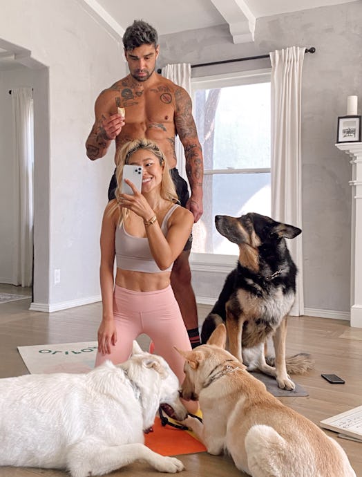 Remi Ishizuka in workout clothes taking a selfie with her boyfriend and three German Shepherds at ho...