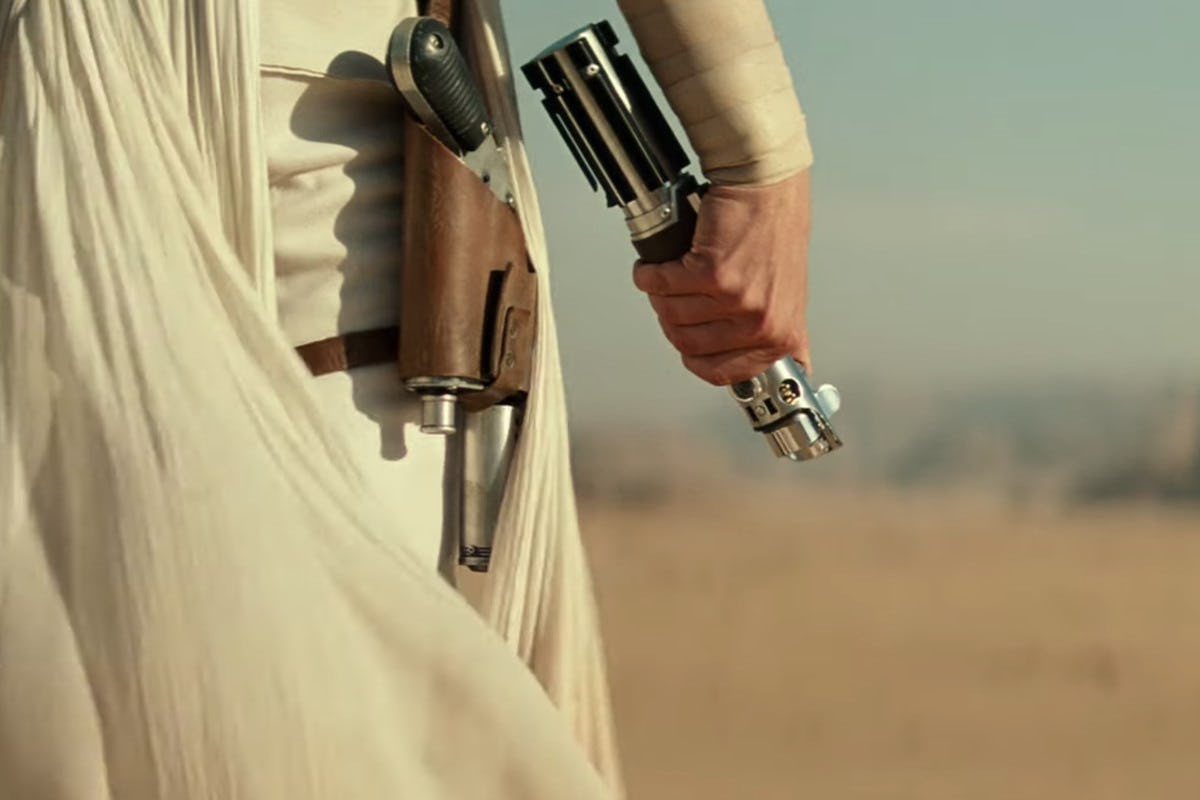 Unactivated lightsaber held by a hand in the desert 