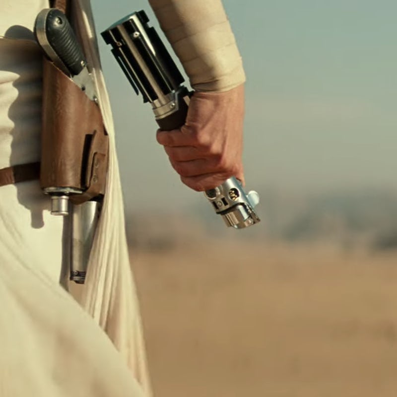 Unactivated lightsaber held by a hand in the desert 