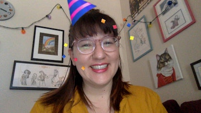 A happy woman smiles with a party hat filter on her head. 