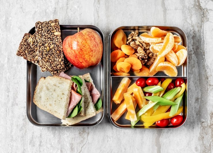 Different types of fruit and sandwiches served on metal square-shaped plates