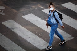a pregnant woman in a face mask walks in Paris during COVID-19