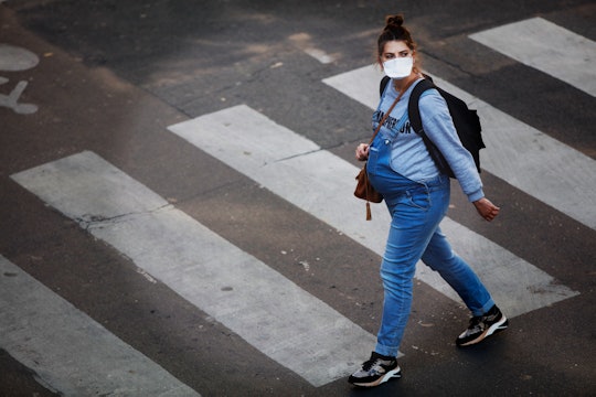 a pregnant woman in a face mask walks in Paris during COVID-19