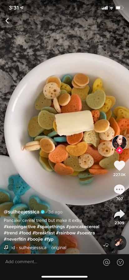 A young woman makes rainbow heart pancake cereal and puts it in a bowl with butter on TikTok.