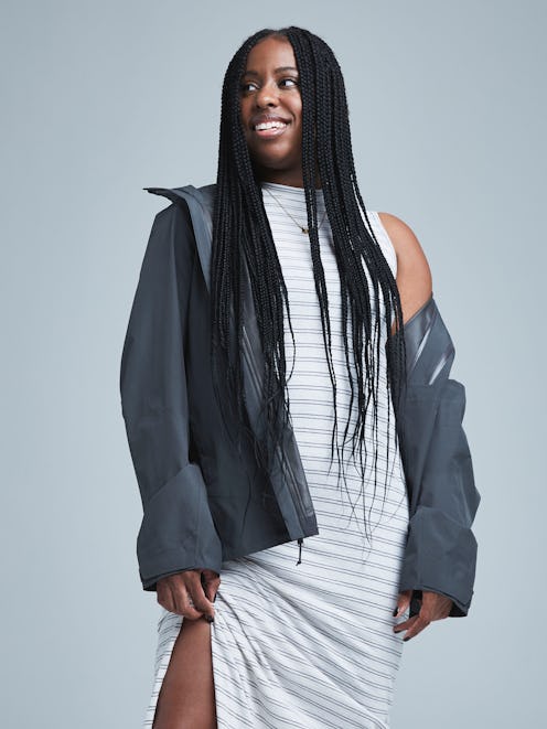 A woman with a long dread hairstyle wearing a white-and-grey striped cotton dress with a side slit u...