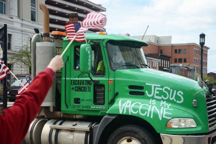 A truck bearing the message "Jesus is my vaccine" blares its siren in support while passin...