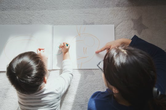 Little boy and mother lie prone on floor coloring paper