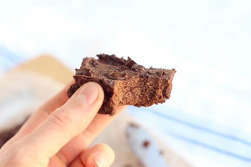 A hand holding a dark chocolate covered brownie.