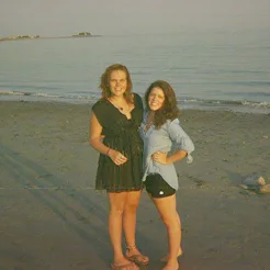 Two female friends celebrating their friendship milestone on a sand beach