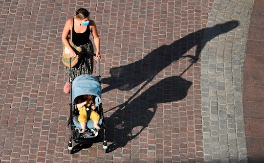 Mother in face mask pushes baby in stroller 