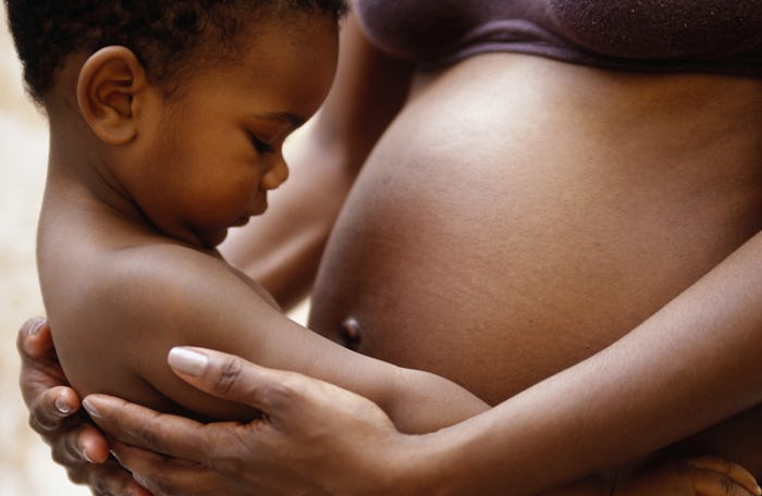 A pregnant mother holds her toddler