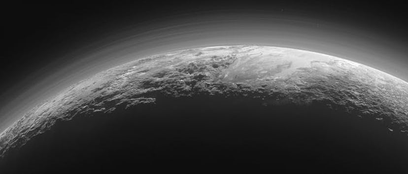 Near-sunset view of Pluto’s rugged, icy mountains and flat plains