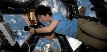 A female astronaut in space floating in a small room with equipment