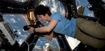 A female astronaut in space floating in a small room with equipment