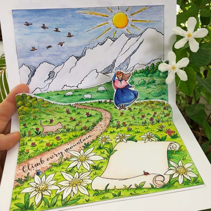 A brightly colored pop-up card with flowers, a trail with script written upon it reading "climb ever...