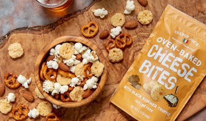 A bag of Trader Joe's oven-baked cheese bites sits next to a bowl of cheesy truffle snack mix.