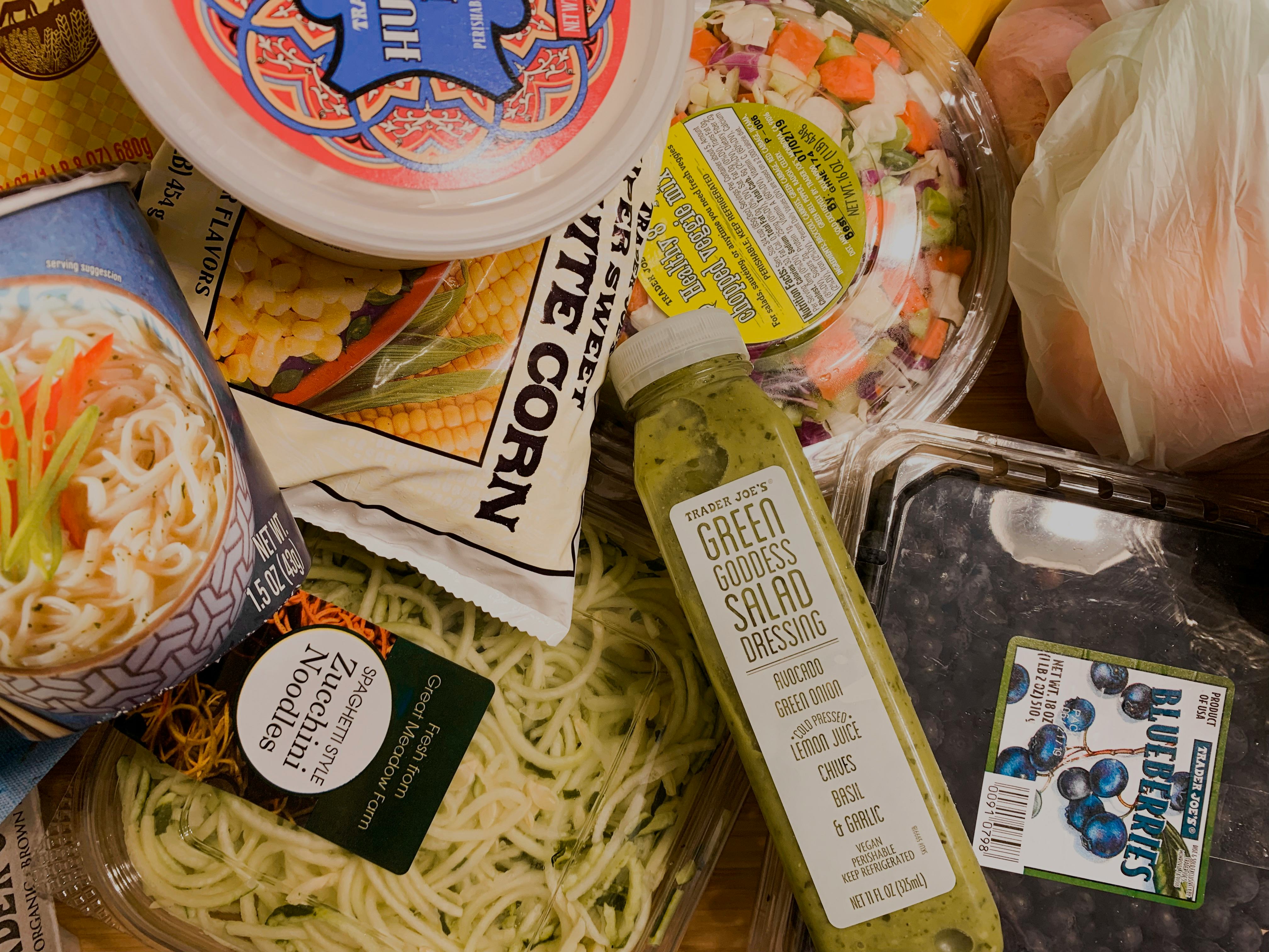 A kitchen table is filled with groceries and snacks from Trader Joe's.