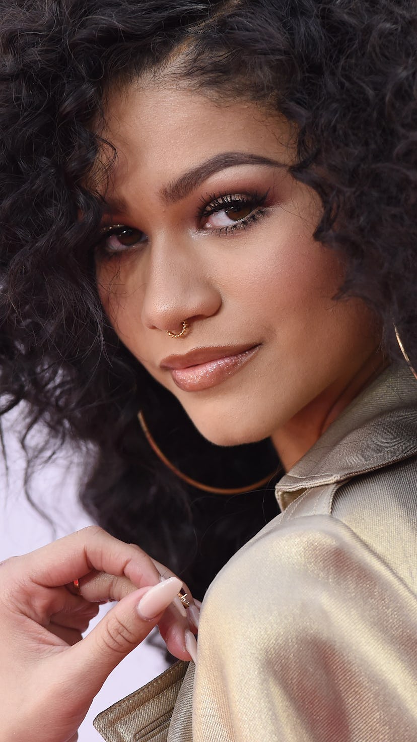 Zendaya wearing a gold jacket, glittery eyeshadow and a golden septum piercing