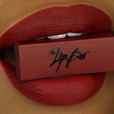 Female lips holding the Lip Bar's Bawse Lady Lipstick shade