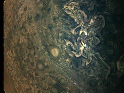 An aerial view of Jupiter's surface in dark green and brown shades