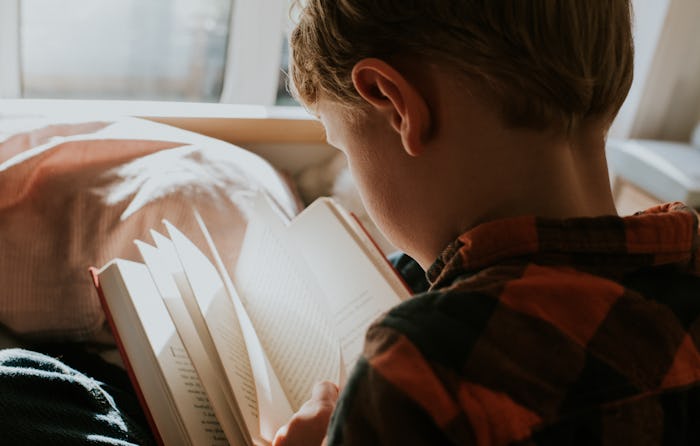 boy reading book in bed