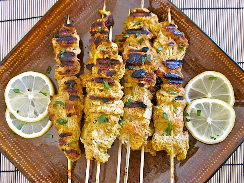 Grilled chicken thigh skewers on a brown plate.