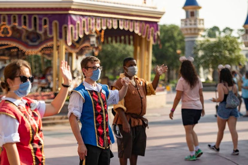 Disney world workers wearing their surgical masks, helping visitors to navigate through. 