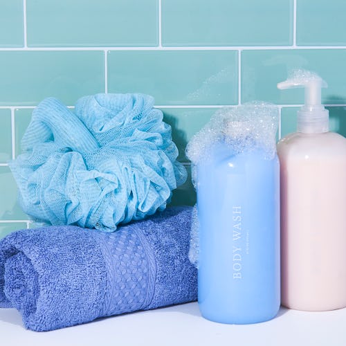 Two shampoo bottles, a blue towel, and a blue hair sponge stacked next to each other