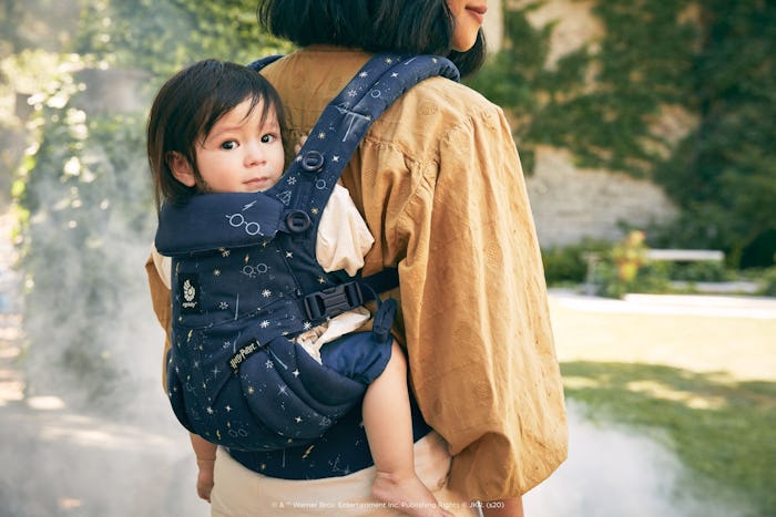 A picture of a woman with a baby in a front facing carrier with Harry Potter imagery on the front. 