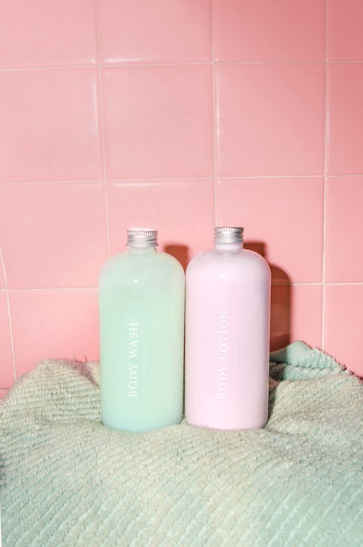 A green and a pink shampoo bottle on a green towel