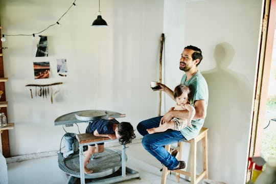 Dad sitting on stool with child, and second child hiding under table