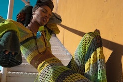 A woman posing in green-yellow-black crocheted custom designed clothing