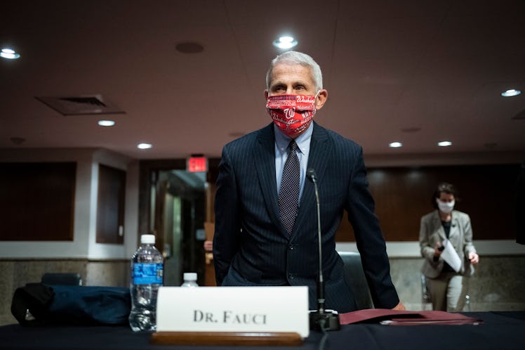 Dr. Fauci in a black suit and a red face mask giving a speech