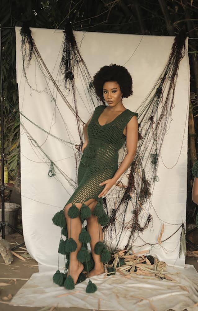 A woman posing in a dark green custom designed crocheted dress
