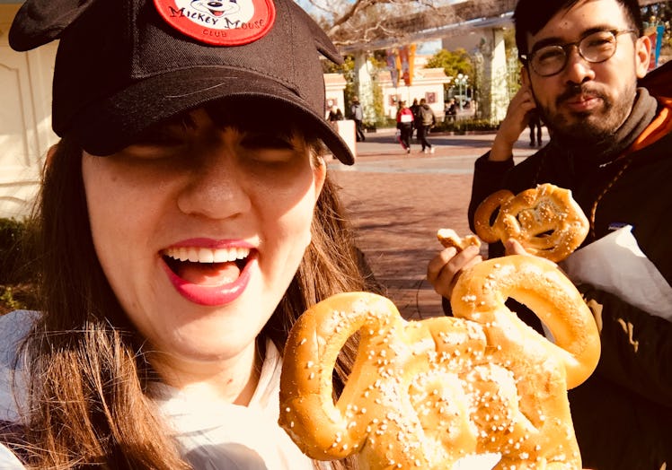 Happy friends hold up their Mickey Mouse pretzels at Disneyland. 