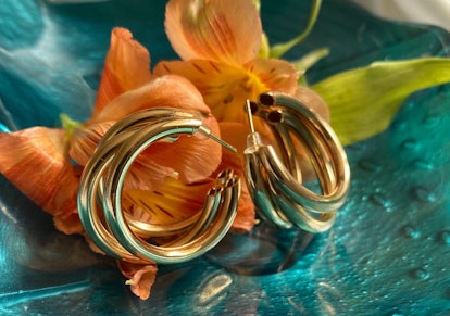 Gold hoop earrings with flowers on a glass dish