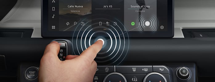A finger is hovering over a touchscreen in a Jaguar model, playing a song on the screen.