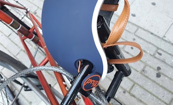 A bicycle helmet with a d-lock through a hole in the rear of it.