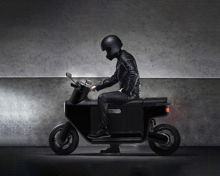 A person wearing all black sitting on a black scooter.