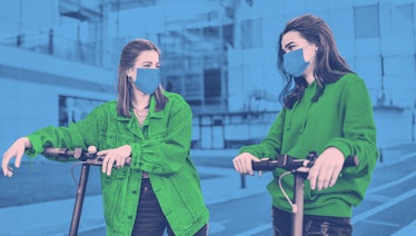 Two girls in green shirts leaning on their electric scooters while wearing masks during the pandemic...