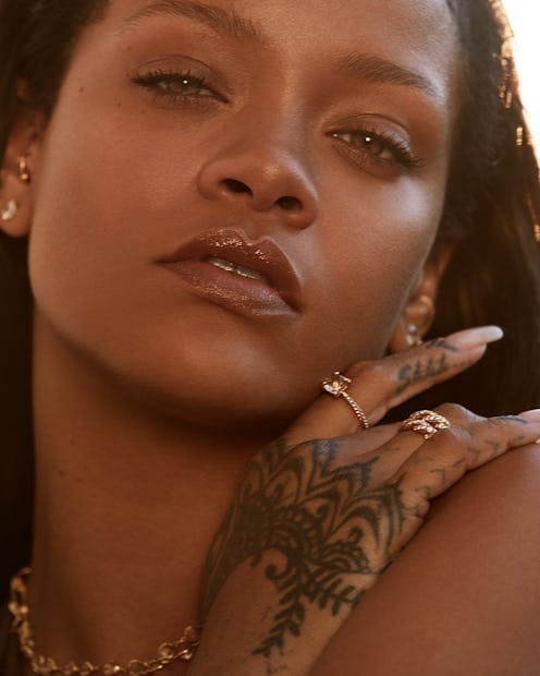 A closeup of Rihanna with her hand on her shoulder, covered in henna