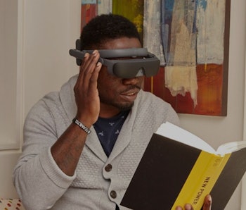 Man reading a book wearing an eSight 4 visual assistance headset.