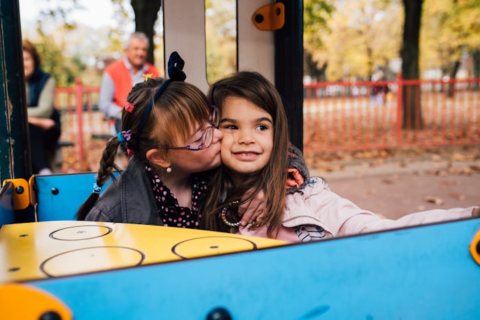 Little girl with Down syndrome hugging and kissing her best friend . 