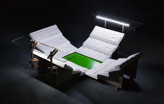A sports stadium made up of keyboard stands and a green screen for a field can be seen. It has typic...