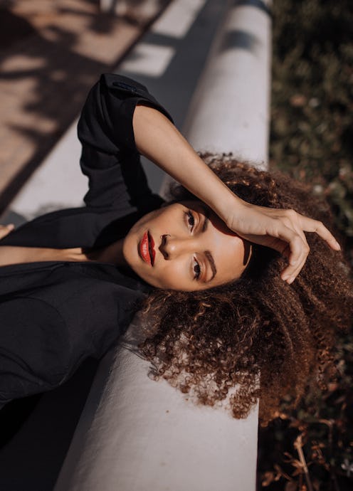 Kendall Keith, model and actor poses outside with her hand on her head in a black button up shirt