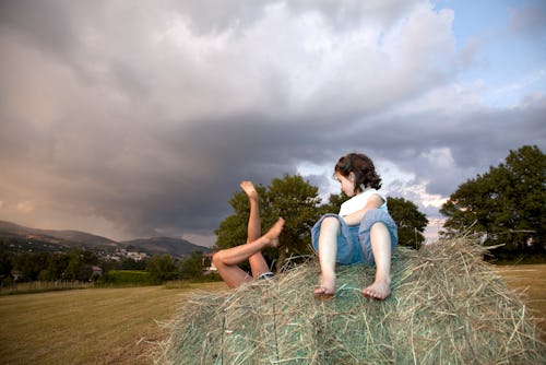Two girls play on a bale of hay in France