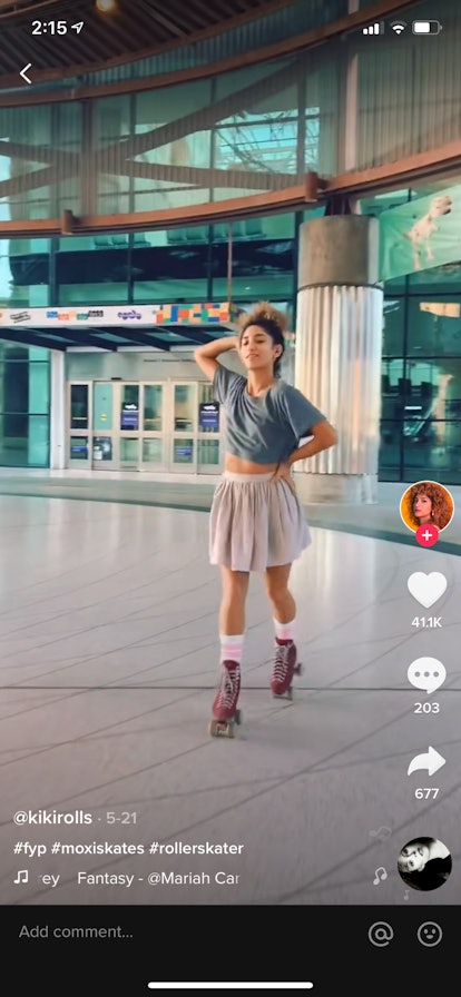 A young Black woman roller skates near a movie theater and poses for a TikTok video.