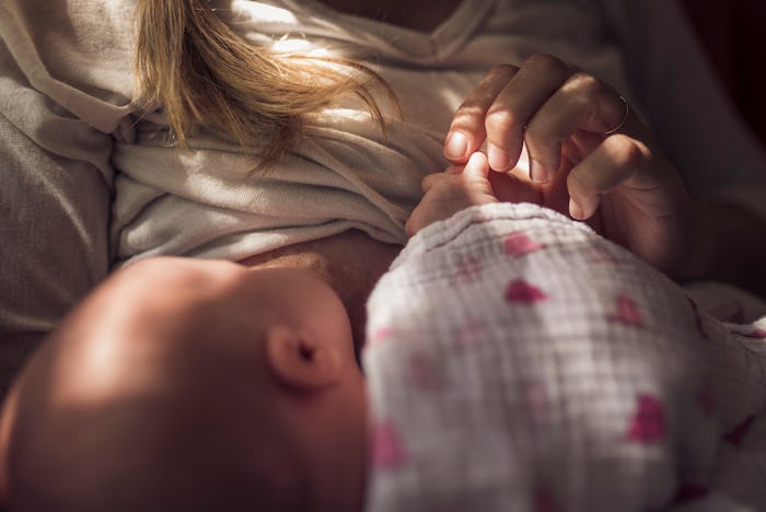 Midsection of mother breastfeeding newborn daughter at home.